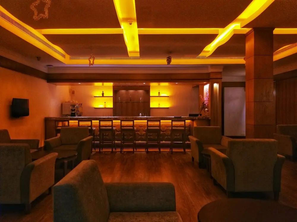 Empty hotel lounge bar at night, amber cove lighting, armchairs and a row of bar stools