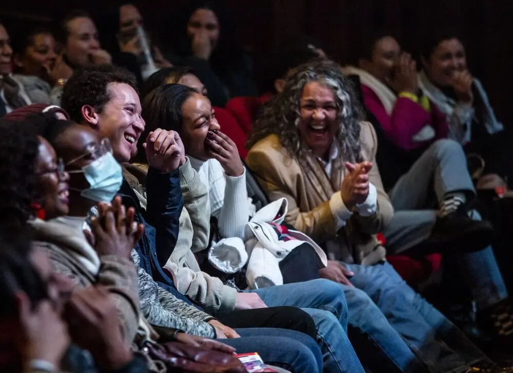 Audience members laughing hard in their seats at the festival.