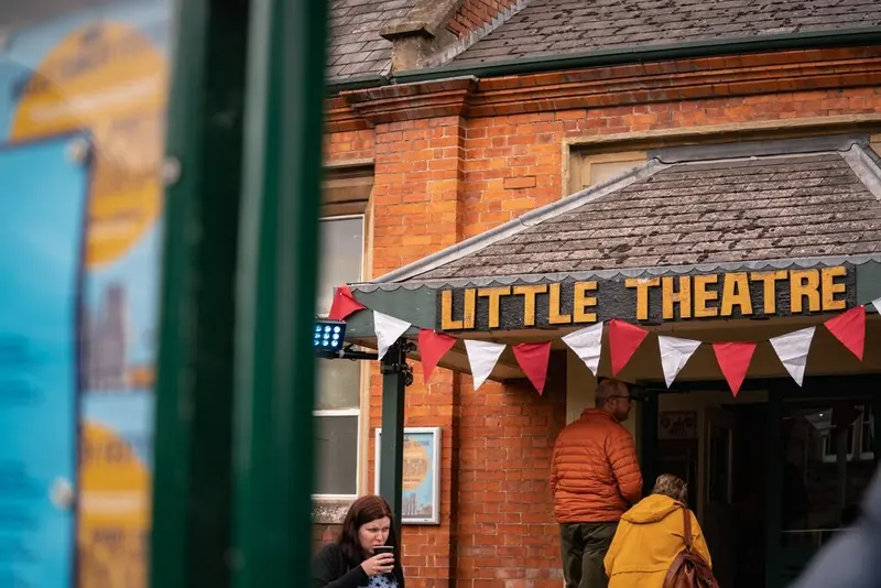 Festival-goers heading into the Little Theatre in Wells under red and white bunting