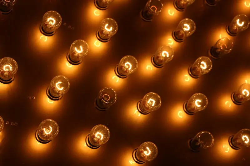 A field of bare amber marquee bulbs glowing on a dark panel, no letters