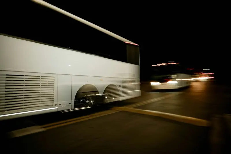 A plain white coach passing in the dark, motion-blurred, no lettering